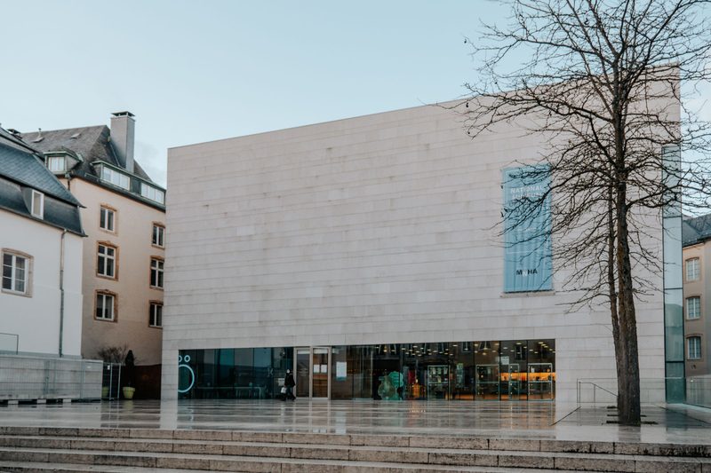 A contemporary museum building with a pale brick façade and a glass ground floor.